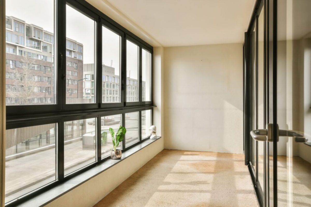 an empty room with large windows and plants in the window sid on the right hand side of the room