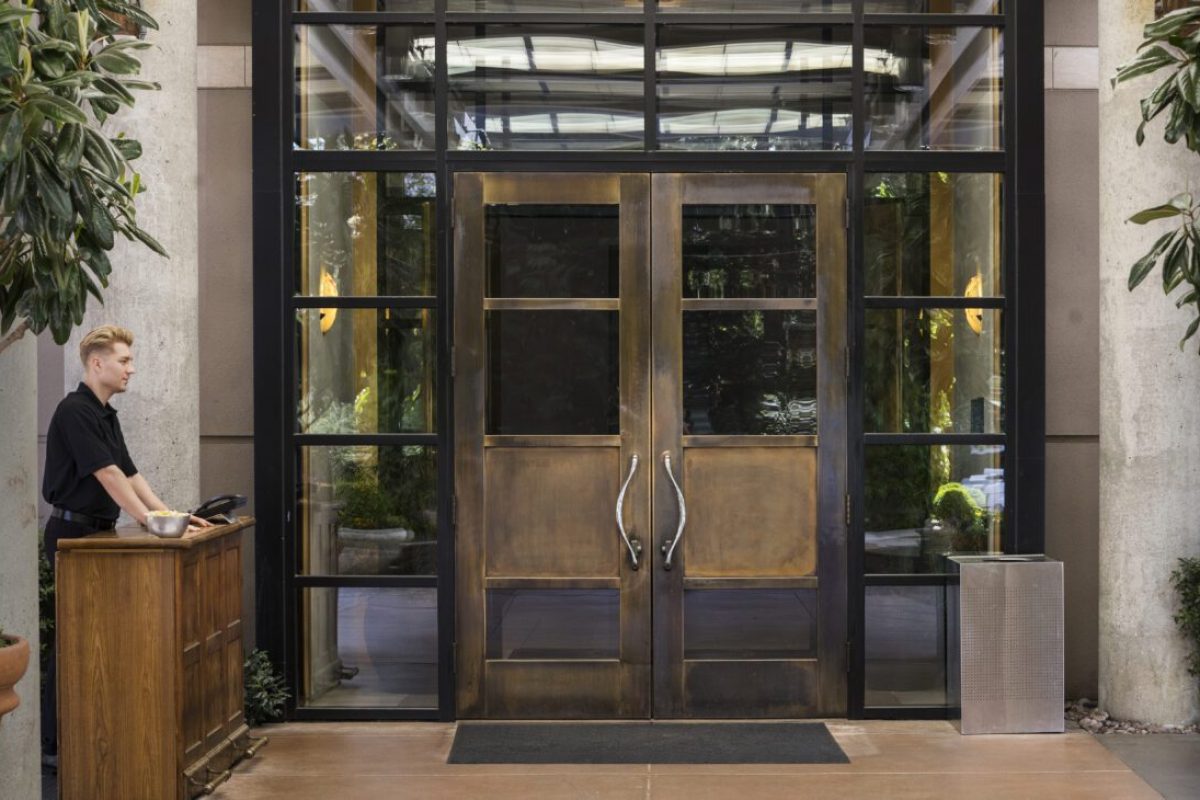 Bellhop standing at wooden reception desk of a downtown hotel.