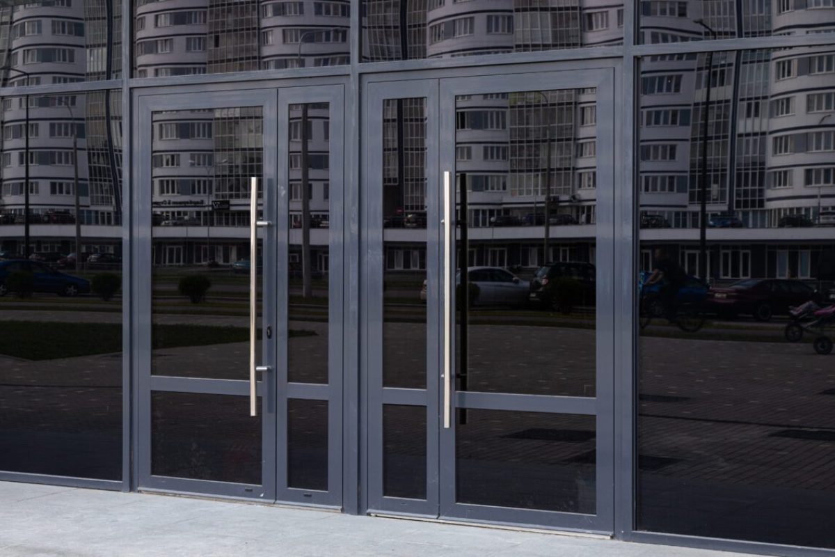 Black glass doors reflecting tenement house standing in the opposite side
