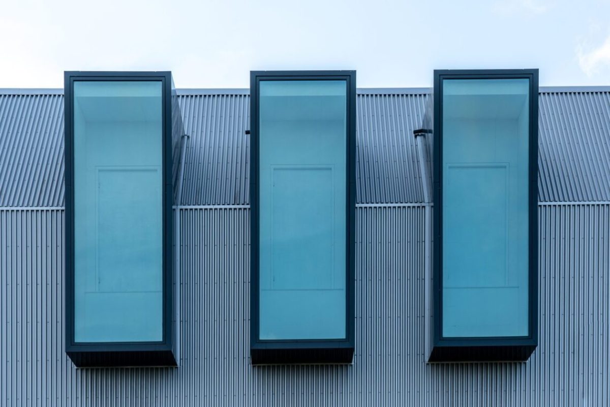 A fragment of a modern building metal sheet facade with three windows in a row