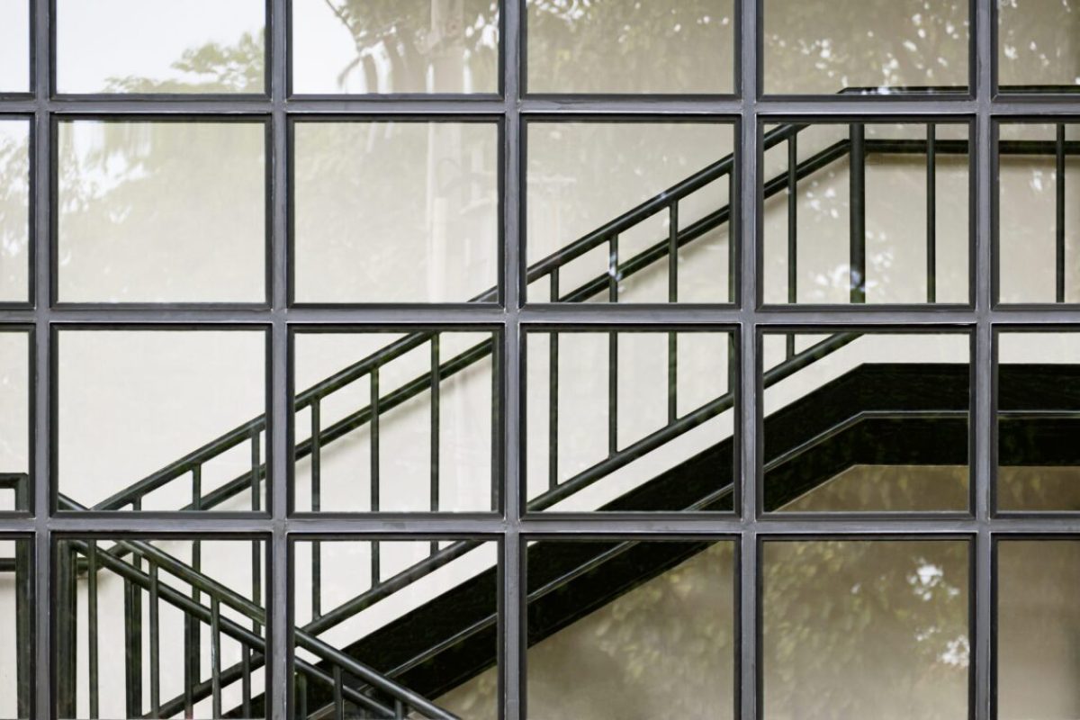 Geometric pattern of glass wall with black metal staircase inside of modern building