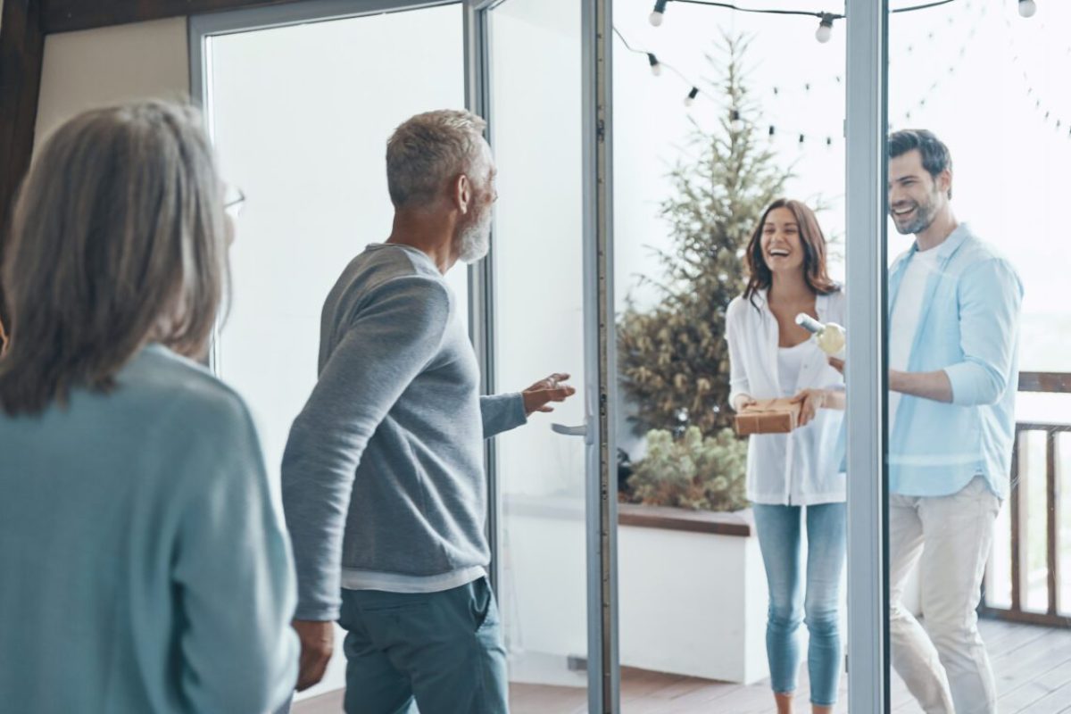 Happy senior parents meeting young couple inside the house