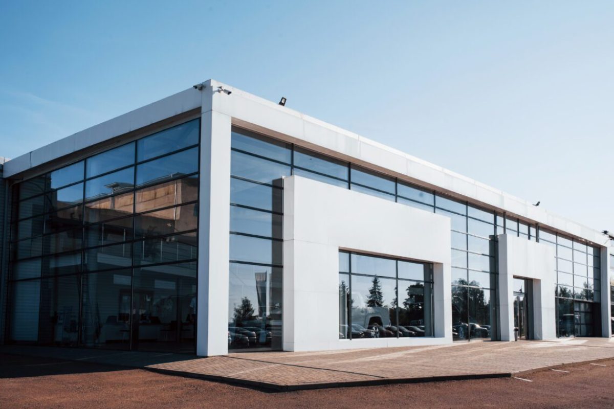 Modern car building. Many vehicles inside. Sunny day with clear sky.