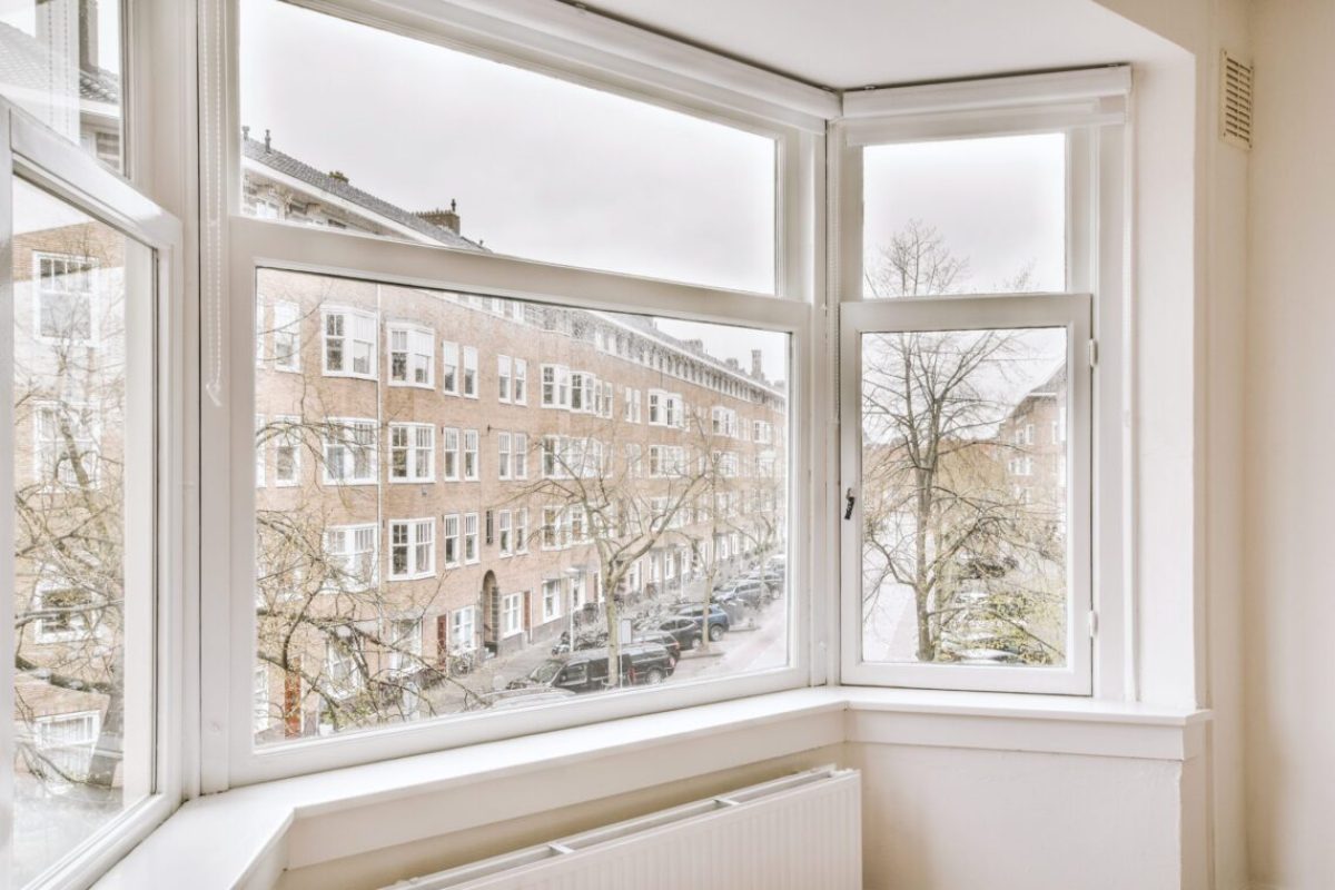 Panoramic view of old brick buildings with parking and trees from small balcony