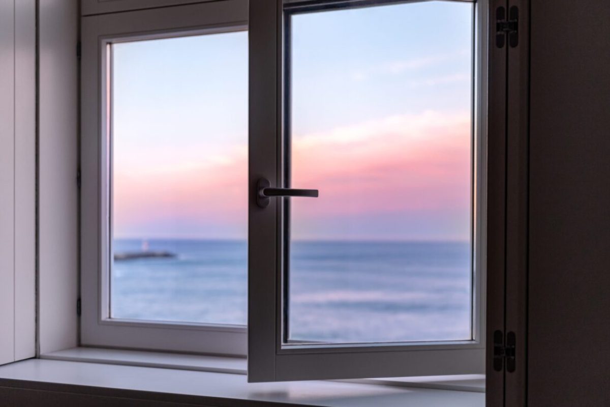 Beautiful pink sunrise over Atlantic Ocean waters in Porto through the open window, Portugal, copy space, postcard concept