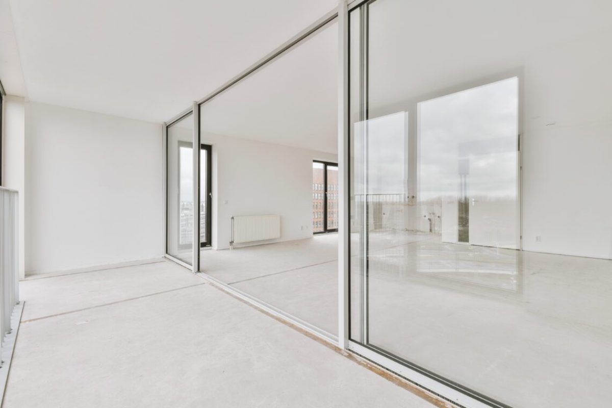 Spacious, empty, bright room with access to a glazed balcony with panoramic windows in a modern house