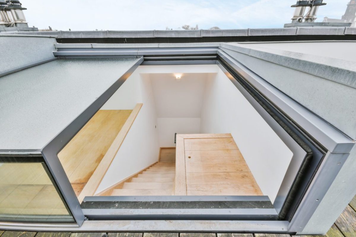 From above of wooden steps with opened window leading to rooftop of modern residential building