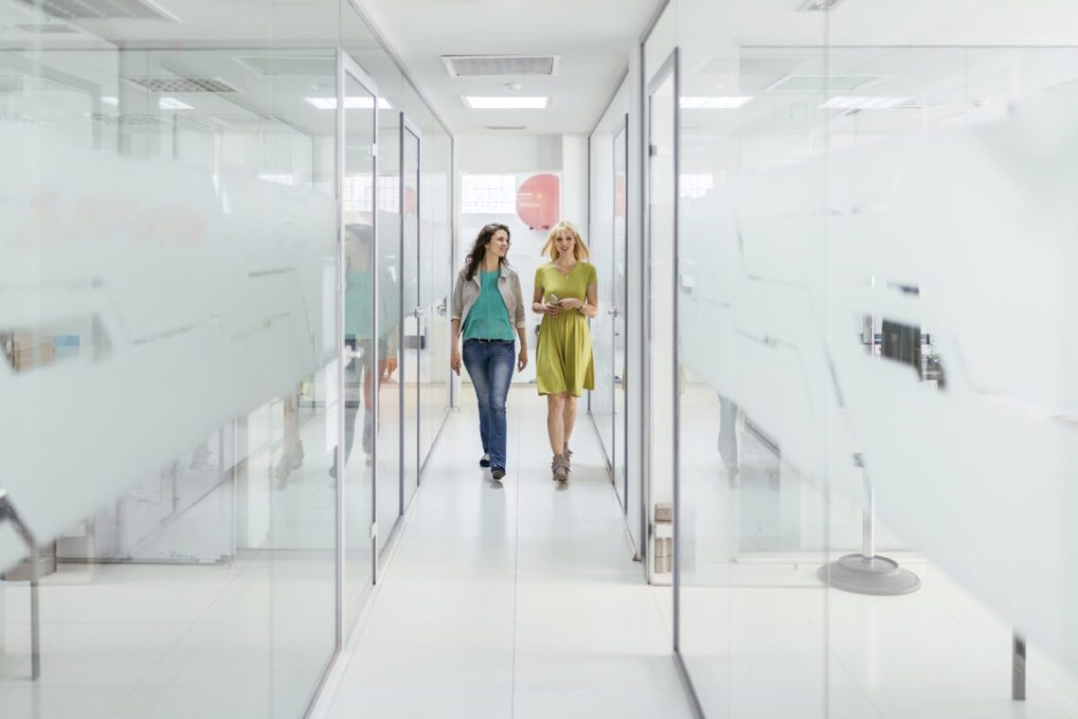 Two female colleagues walking in office corridor