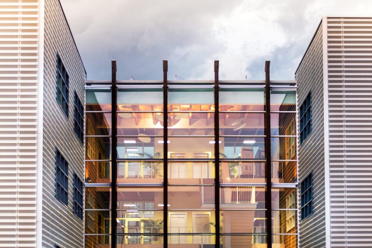 Architectural design of unique modern office building with clouds reflecting on glass.