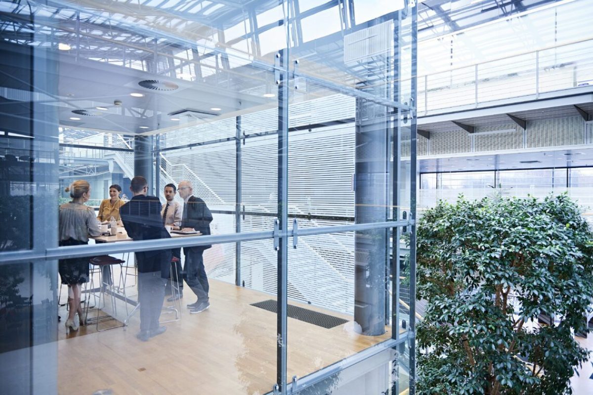 Window view of businesswomen and men having discussion in conference room